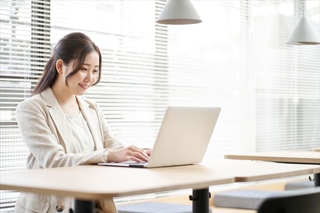 笑顔でノートパソコンのキーボードを入力する女性